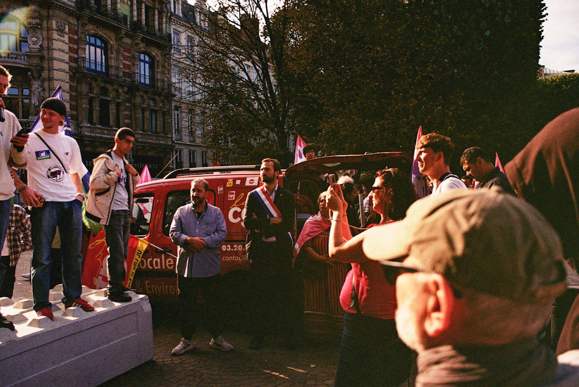 Participants à un événement public extérieur avec des banderoles et drapeaux