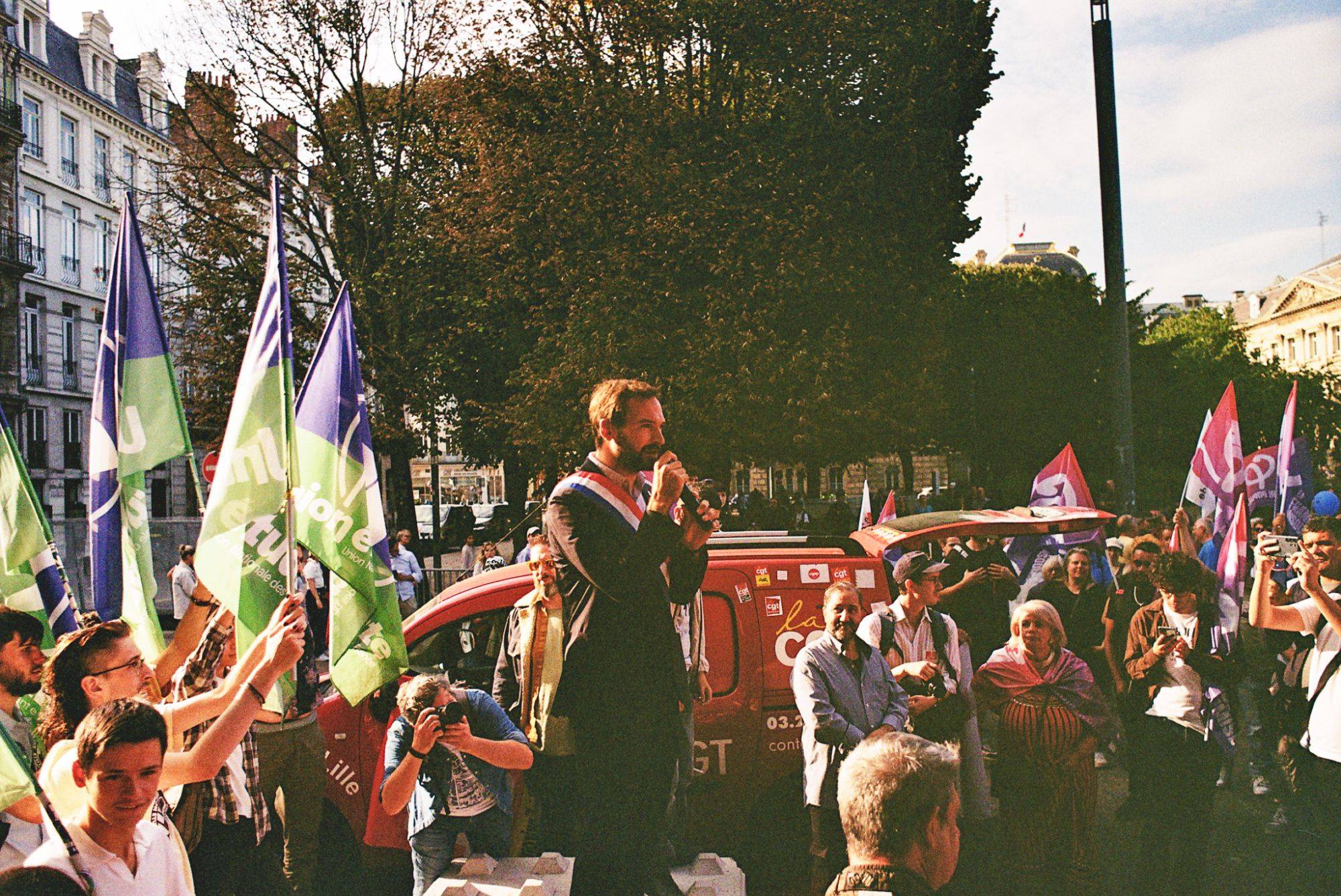 Orateur s'adressant à la foule lors d'un événement extérieur avec drapeaux